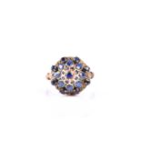 A yellow metal and sapphire princess cluster ring, the domed mount set with pear-cut and round-cut