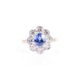 An 18ct yellow gold, diamond, and sapphire cluster ring, set with a mixed oval-cut blue sapphire