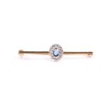 An 18ct yellow gold, diamond, and sapphire bar brooch, set with a mixed oval-cut sapphire within a