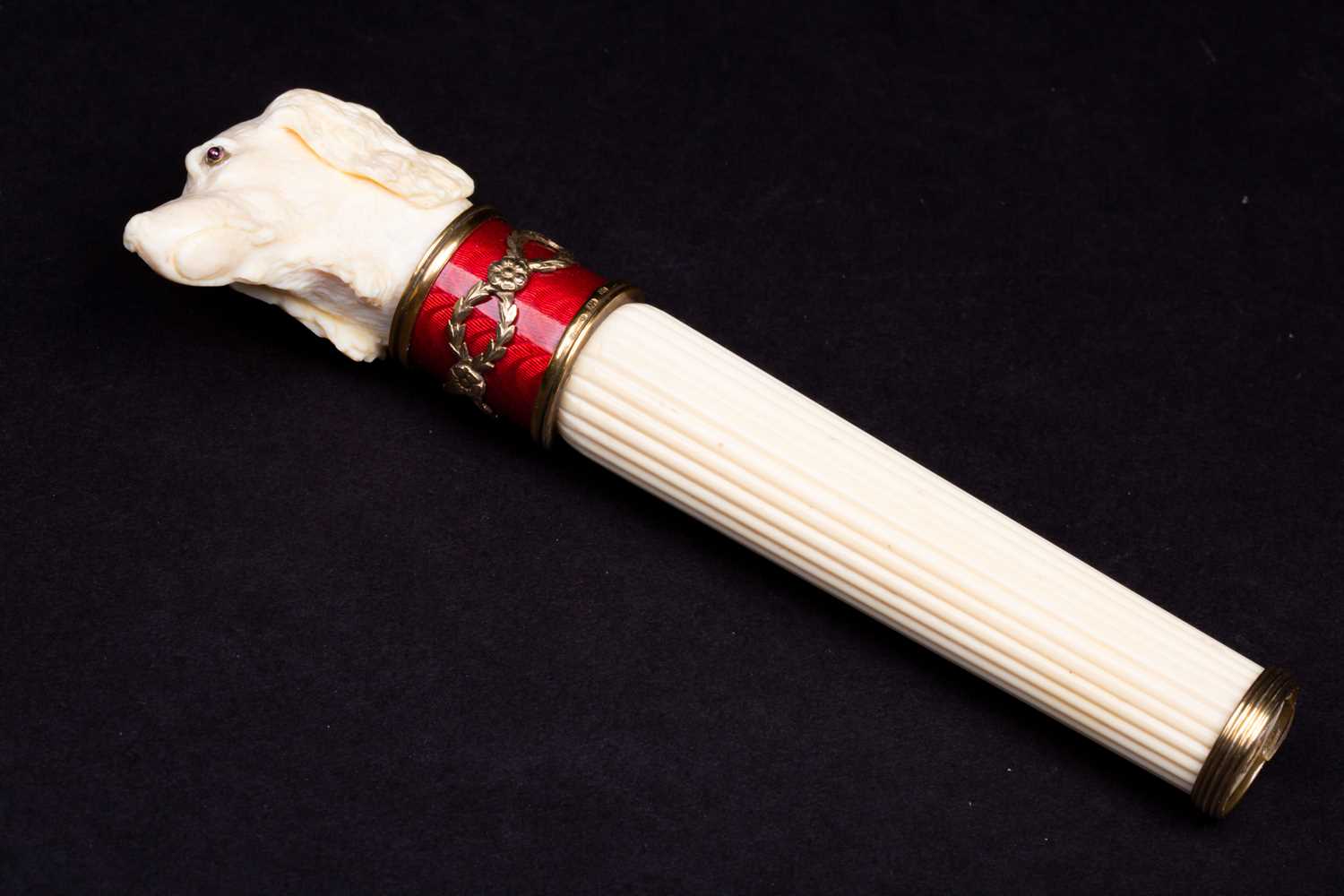 A Russian carved ivory parasol handle, well carved as a dog's head with ruby inset eyes set in