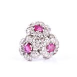 A ruby and diamond cocktail ring, composed of three flowerhead clusters, with central circular cut
