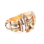 A mid 20th century yellow metal bangle, in the late Deco style of stylised ribbon design, with