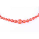 A single row graduated coral bead necklace, the circular beads to a clasp formed as shaking hands,