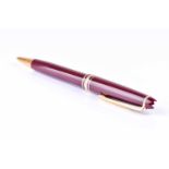 A Montblanc Meisterstuck ballpoint pen, with maroon coloured resin body and cap, and gilt metal