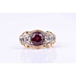 A yellow gold, diamond, and garnet ring, set with a mixed round-cut garnet, 7 mm diameter, the