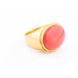 A yellow metal and cabochon coral ring, the coral measuring approx 22 mm x 17 mm, the ring stamped