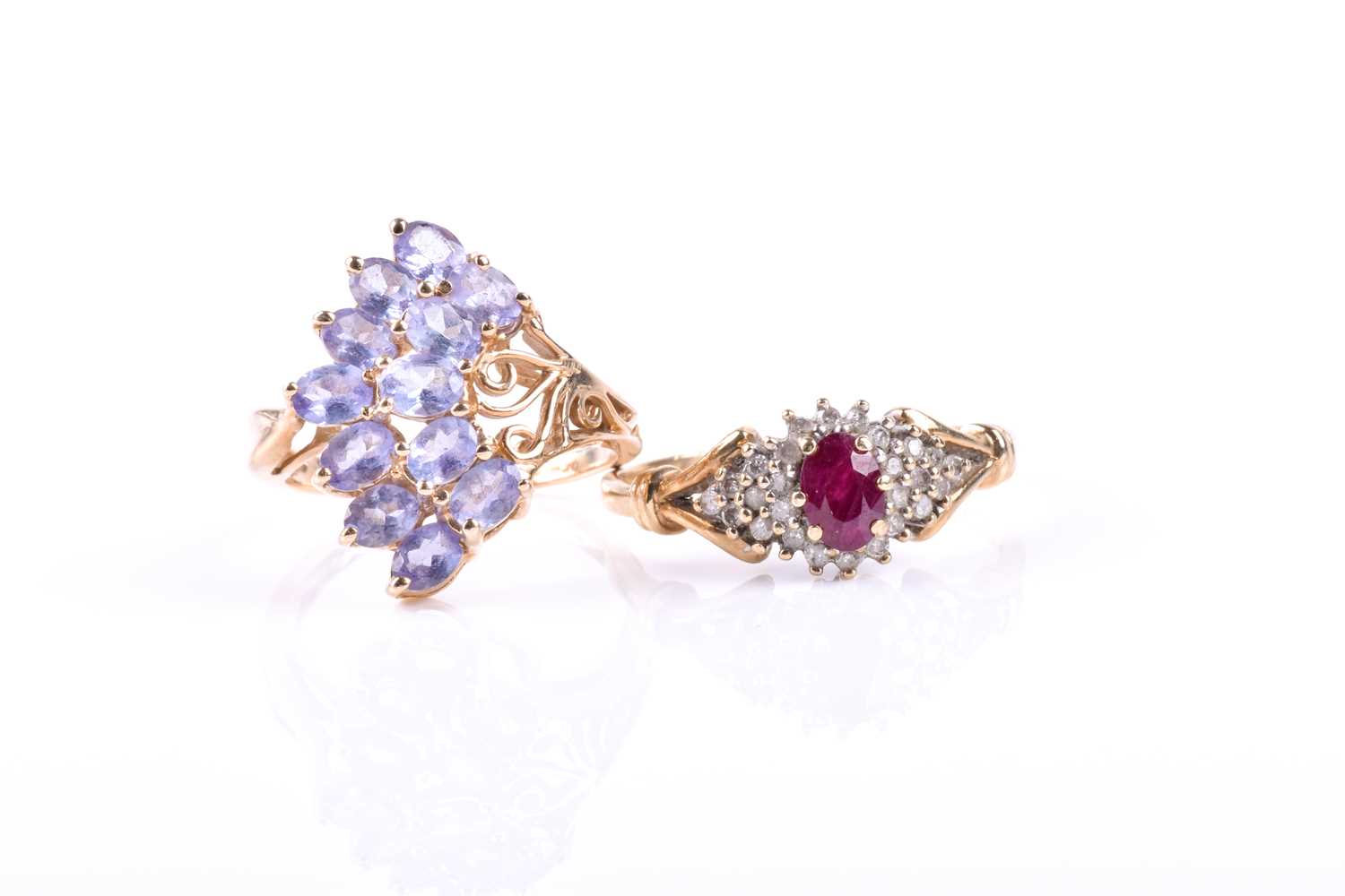 A ruby and diamond cluster ring, the central oval cut ruby, within tiered bands of single cut