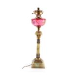 A Victorian onyx and champleve enamel oil lamp, with cranberry glass reservoir etched with a gilt