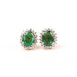 A pair of diamond and emerald cluster earrings, set with mixed oval-cut emeralds of approximately