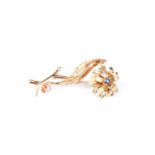 An 18 carat gold and sapphire flower brooch; the circular cut sapphire to flowerhead centre,