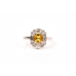 A platinum, diamond, and yellow sapphire ring, in the Art Deco style, set with a mixed-cut