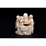 A Japanese ivory netsuke, Meiji period, carved as a man with attendants with avian heads around a