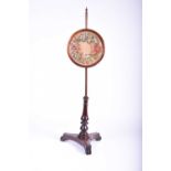 An early 19th century Rosewood pole screen, the circular adjustable panel with floral needlework, on