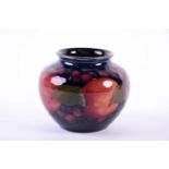 A small early 20th century Moorcroft posy pot in the Pomegranate pattern on a deep blue ground, with