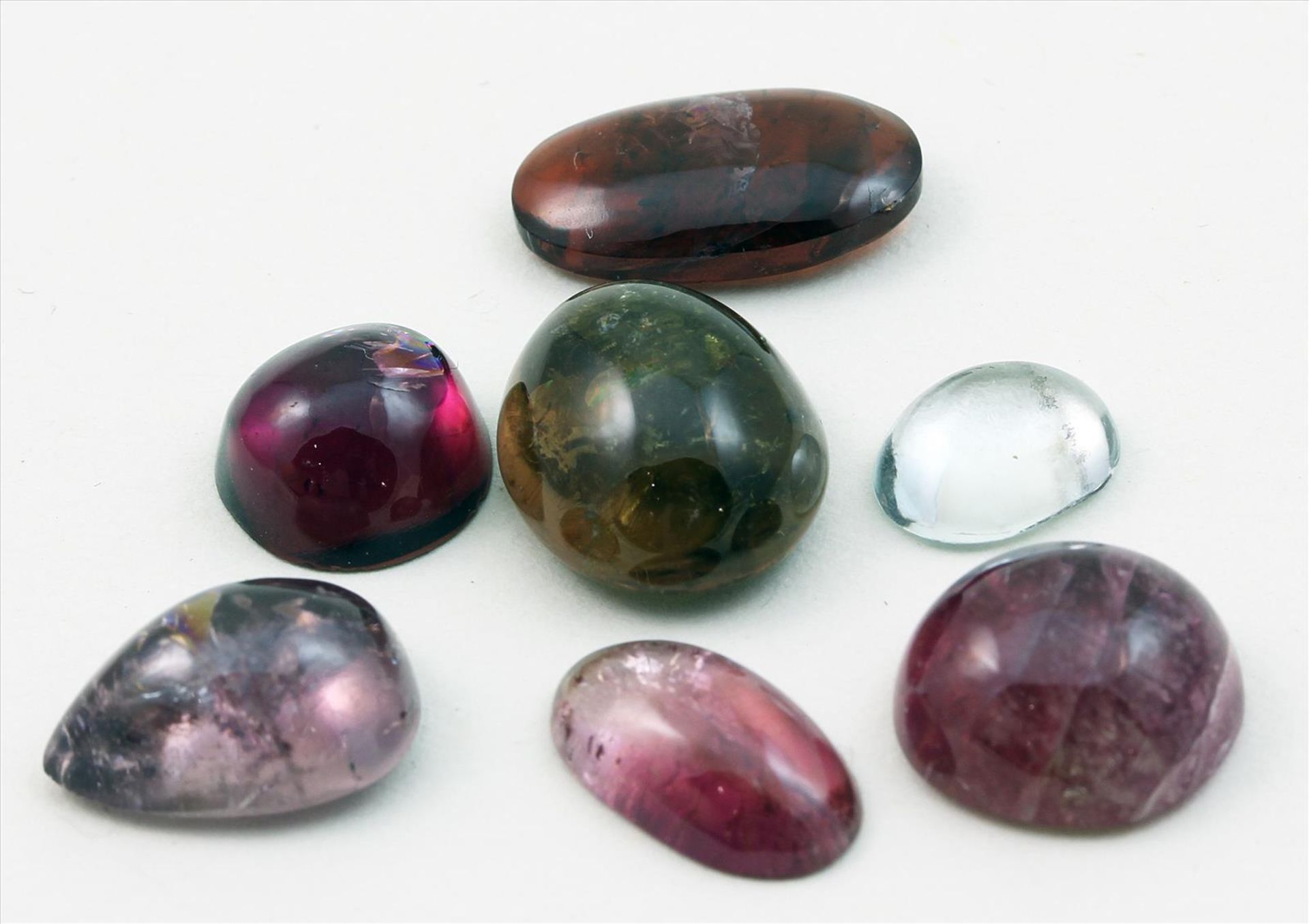 Sieben Turmaline, zus. 26,62 ct.Cabochons in verschiedenen Formen. Überwiegend Rosé- bzw. Brauntöne,