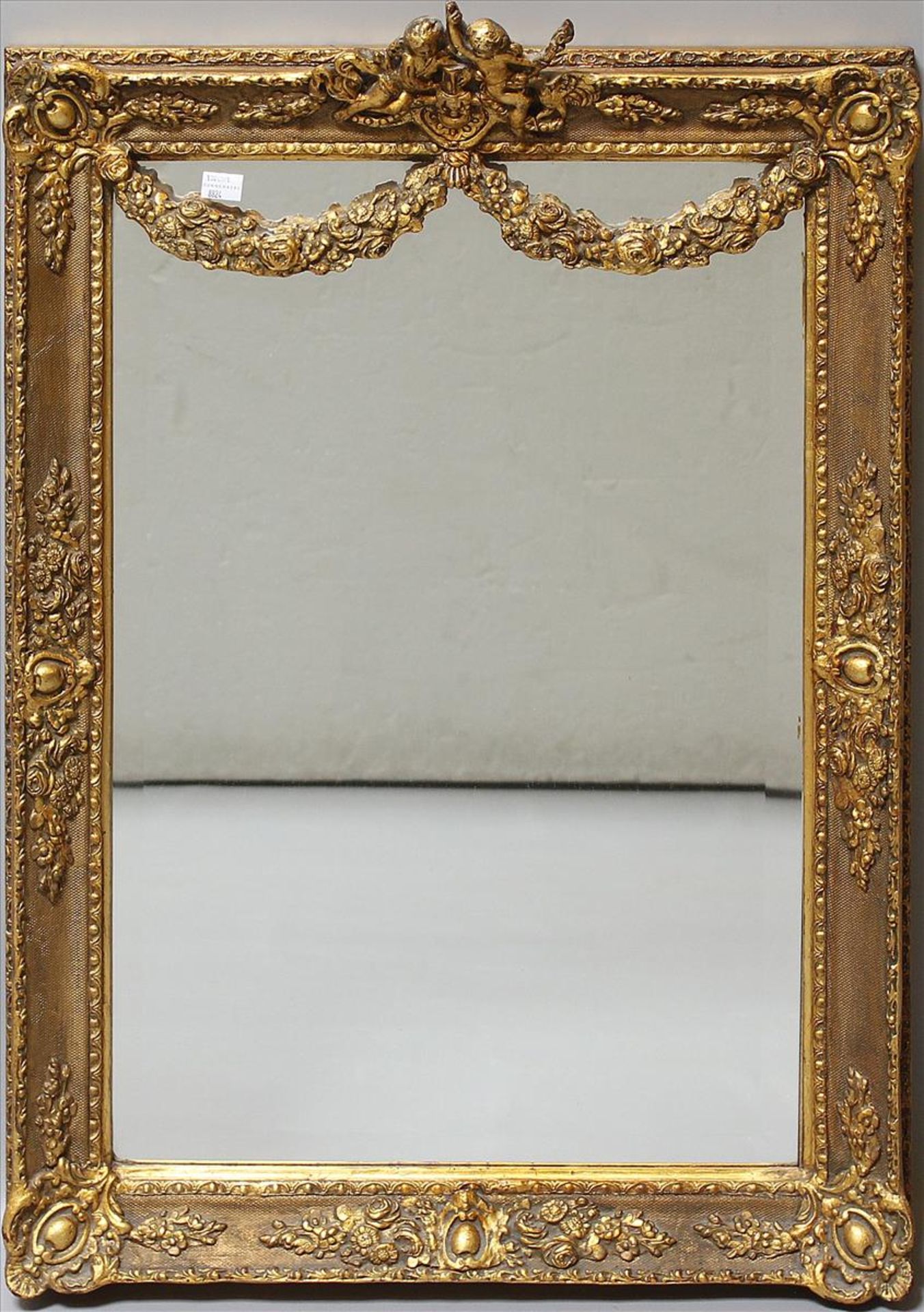 Prunkspiegel im Stil Louis XVI. (Anf. 20. Jh.).Stuck, vergoldet. Plastische Bekrönung mit 2 Putten