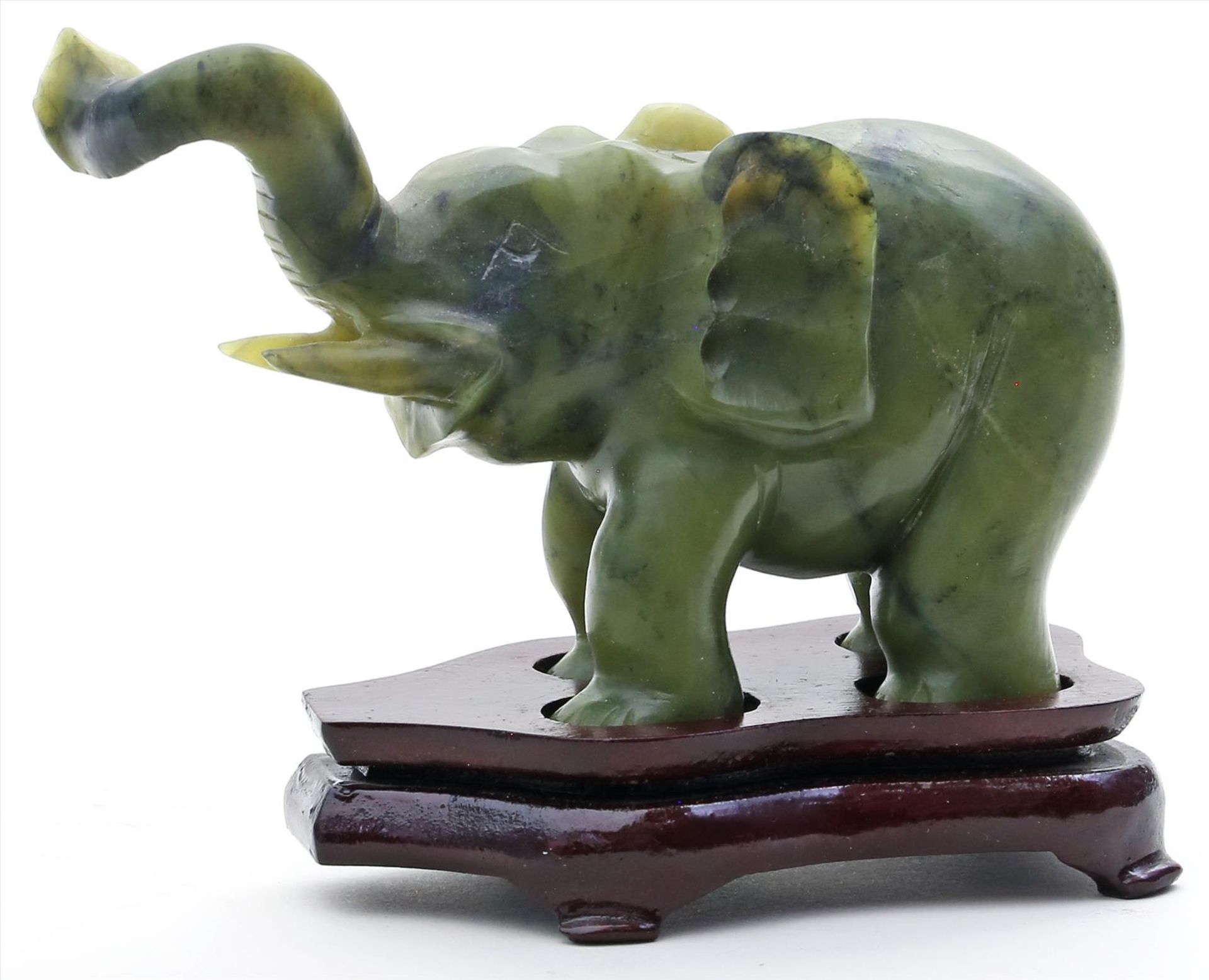 Stehender Elefant mit erhobenem Rüssel.Jadefarbener Steatit. China.H. 8 cm. Beigegeben: Holzsockel.