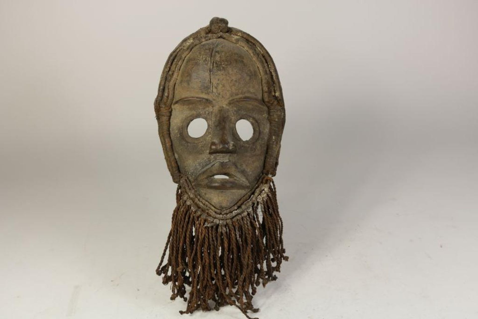Mask, Côte d'Ivoire, l. 32 cm.Aangezichtsmasker met plantenvezel omkranst, Ivoorkust, Dan, l. 32