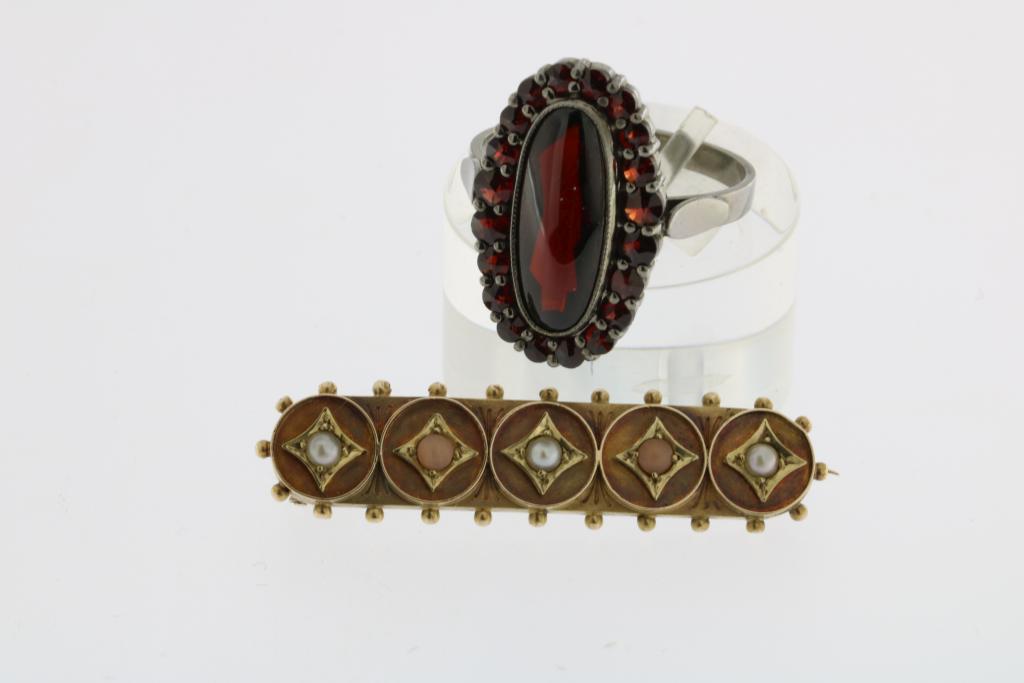 A ring set with garnet and a barbrooch set with three seedpearls.Lot met ring met granaat en