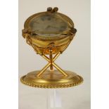 G. B. & Sons bronze shelf clock. Timpani form case on a tripod support resting on a round base, sold