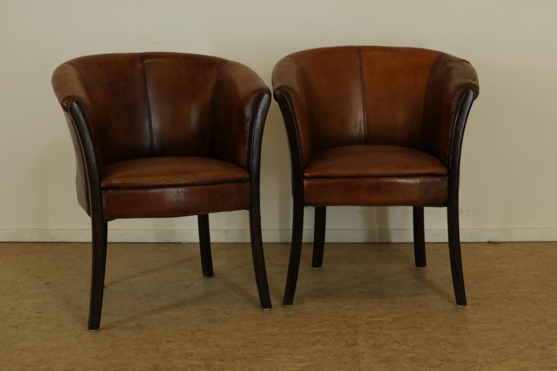 Pair of 2 leather club chairsStel clubfateuils bekleed met leer en siernagels, rustend op eiken