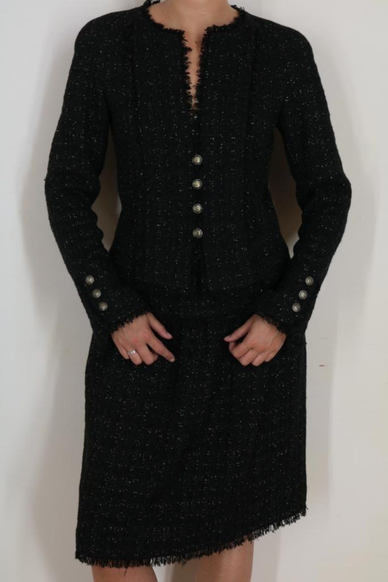 Zwart Chanel tweed mantelpak bestaande uit jasje afgezet met rafels, en Chanel knopen en kokerrokje,