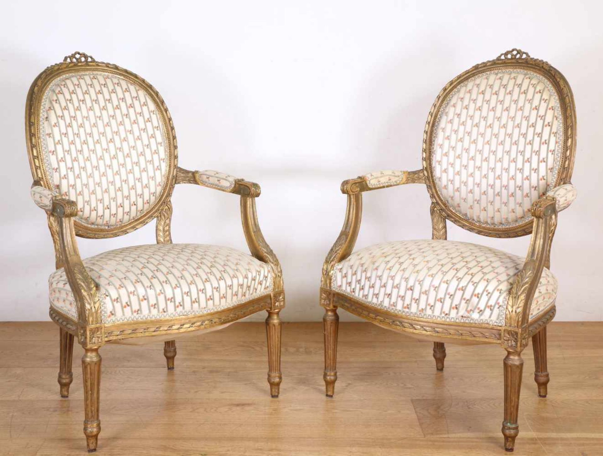 Paar verguld houten fauteuils in Louis XVI-stijl, 19e eeuw,met opengewerkte strik in de kapregel,