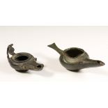 Roman, two bronze oil lamps, one with a dent and an erosion hole, the other missing one grip, 1st-2n