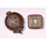 Tibet, amulethouder met reliëf versiering en ronde pigmenten houder met reliëf afbeelding van myth