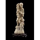 Ivory carved sculpture of a man with child on a rock with a pack of branches in his hand, Japan,