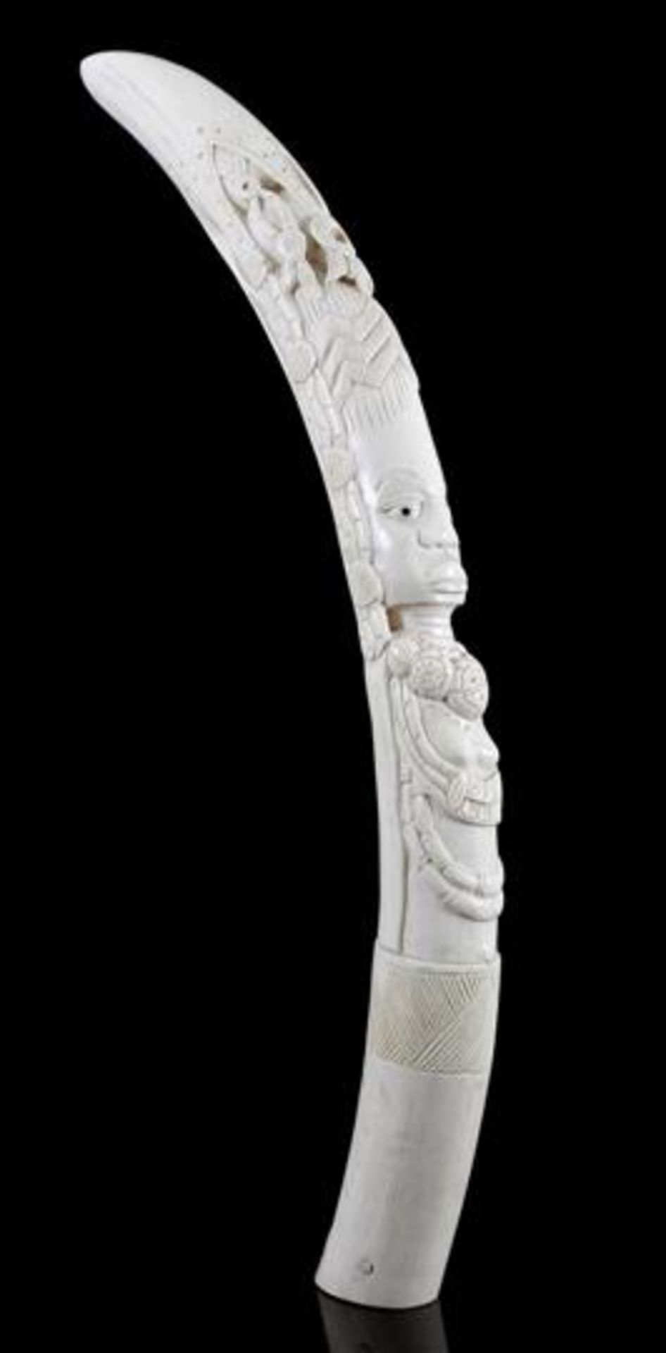 Richly carved ivory tooth with a hand-carved representation of a person with decorative ornaments.