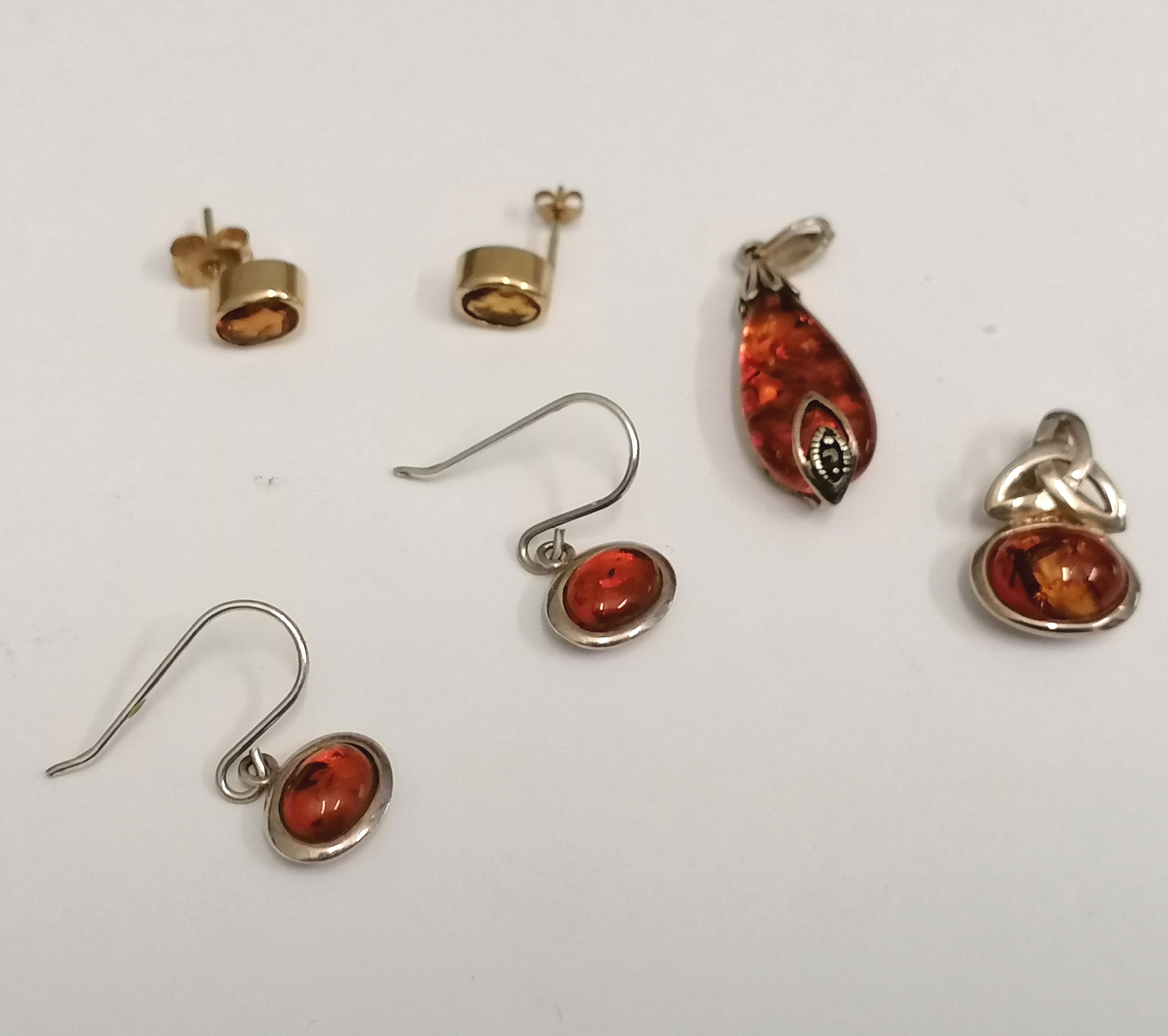A collection of amber jewellery to include two silver and amber pendants, a pair of silver and amber