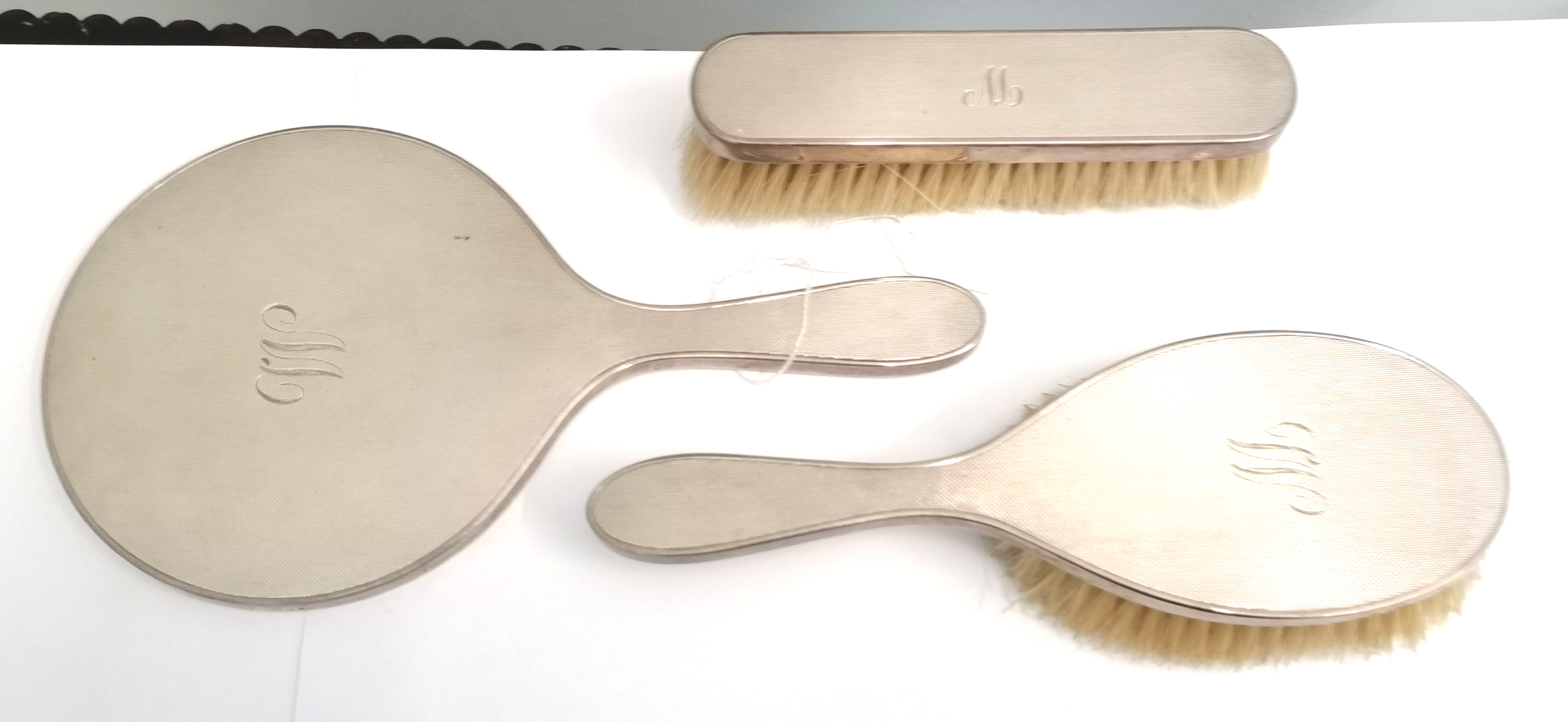 A London silver dressing set by DCBs, comprising of a hand mirror and two brushes, dated 1955