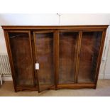 An Edwardian oak bookcase cabinet having four glazed panel doors enclosing six adjustable shelves