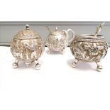 A 19th century eastern white metal salt and pepper having an ornately chased motif depicting