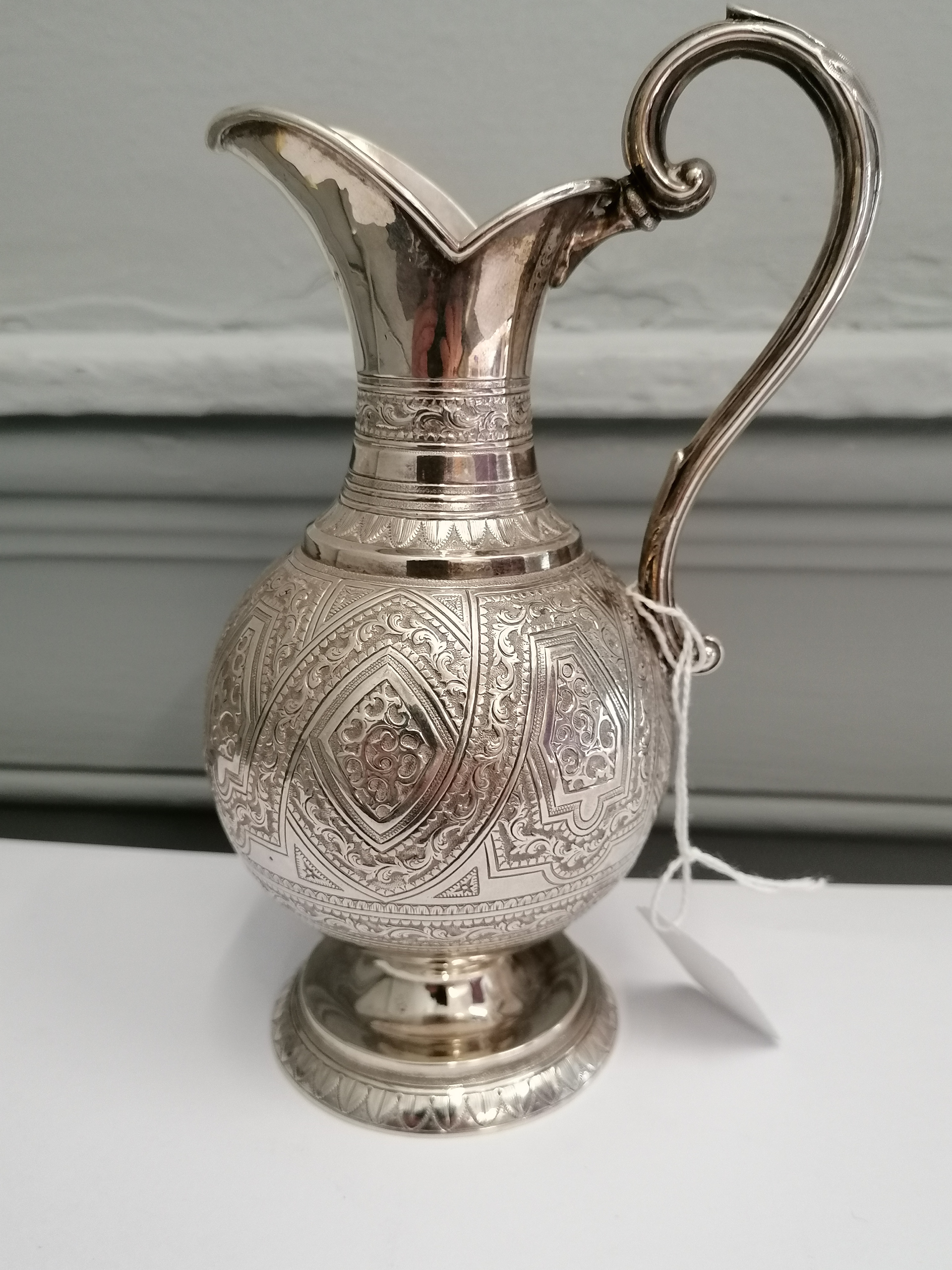 A William Marshall silver cream jug having ornately repousse/chased form on spread pedestal base