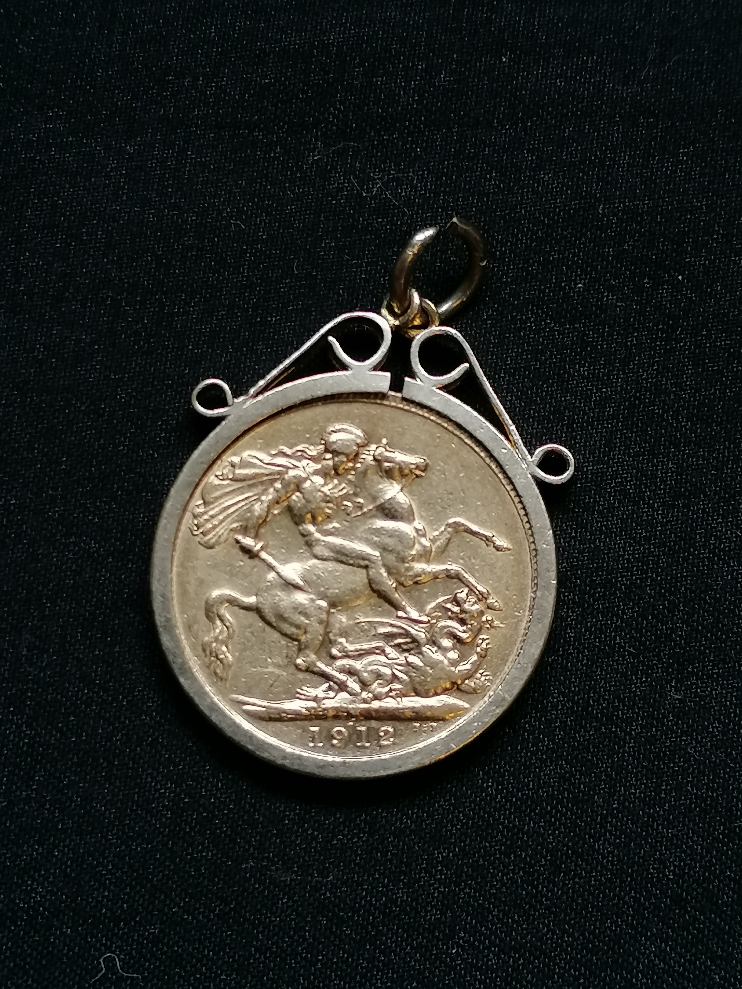 A 1912 gold Sovereign Georgius V in a 9ct gold mount. 10g approximately including mount.