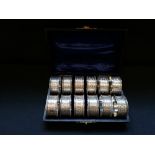 Fine cased set of twelve silver napkin rings decorated with floral chasing and miniature gadroon