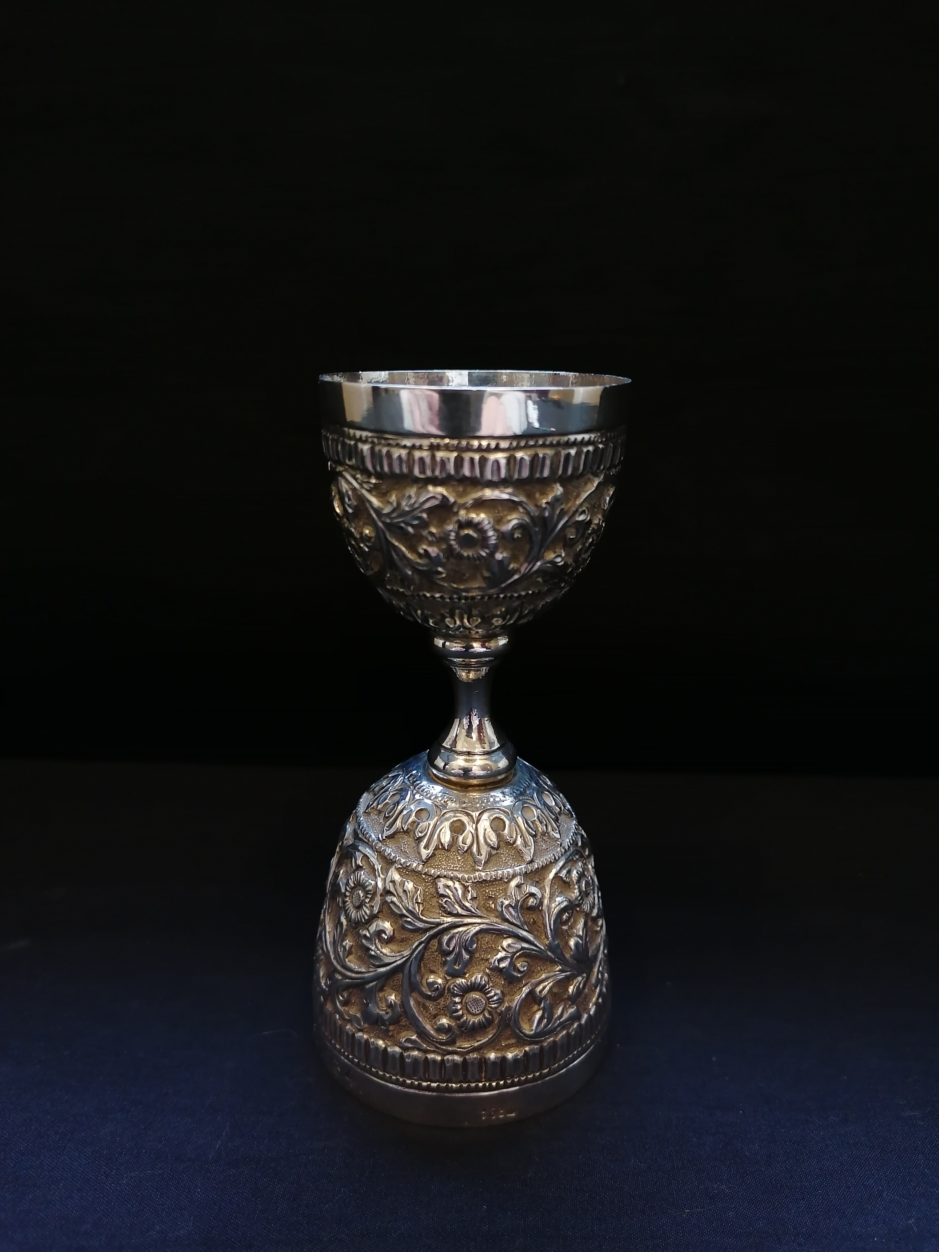 An Indian double sided spirit measure with repousse/chased foliage design engraved 'D.D. Scott