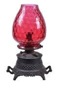 A late Victorian painted spelter and cranberry glass kerosene heater oil lamp