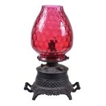 A late Victorian painted spelter and cranberry glass kerosene heater oil lamp