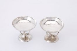 A pair of Arts and Crafts spot hammered silver pedestal dishes by James Weir