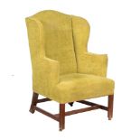 A mahogany and green upholstered wing armchair in George III style