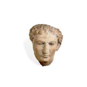 A Roman marble male head with layers of tightly curled hair framing the face, Palmyra, circa AD 200