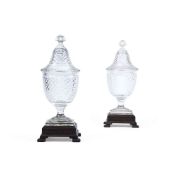 A pair of large Continental cut-glass urns, domed covers and associated carved wood stands, 20th cen