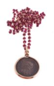 An antique coin pendant on a ruby bead chain