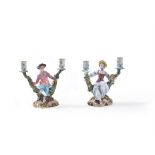 A pair of Meissen two-branch flower-encrusted figural candlesticks depicting gallant and companion