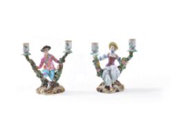 A pair of Meissen two-branch flower-encrusted figural candlesticks depicting gallant and companion