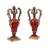 A pair of French gilt metal and red glazed ceramic urn table lamps
