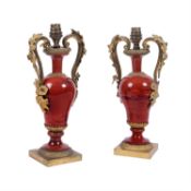 A pair of French gilt metal and red glazed ceramic urn table lamps